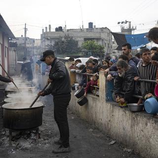 Des Palestiniens attendent la distribution de nourriture à Rafah, dans la bande de Gaza. [AP/Keystone - Fatima Shbair]