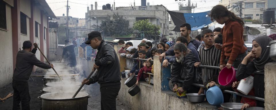 Des Palestiniens attendent la distribution de nourriture à Rafah, dans la bande de Gaza. [AP/Keystone - Fatima Shbair]