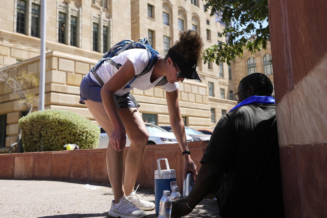 Une bénévole du programme de réponse à la chaleur mené par la ville de Phoenix distribue de l'eau, le 20 juillet. [Keystone - Ross D. Franklin/AP Photo]