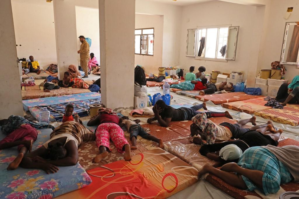 Des migrants originaires de pays d'Afrique subsaharienne, qui affirment avoir été abandonnés dans le désert par les autorités tunisiennes, se reposent dans un abri après avoir été secourus par des gardes-frontières libyens près de la ville frontalière d'Al-Assah, le 16 juillet 2023. [AFP - MAHMUD TURKIA]