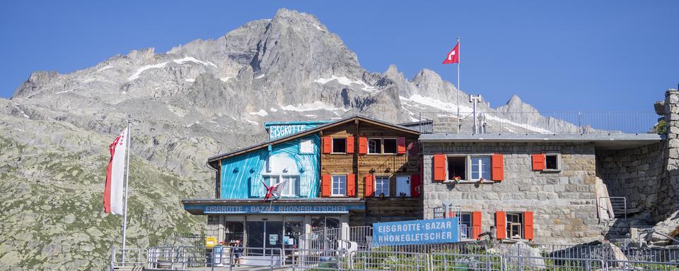 L'entrée de la grotte de glace du glacier du Rhône avec le bazar de la famille Carlen, au col de la Furka, le 11 juillet 2023. [Keystone - Urs Flueeler]