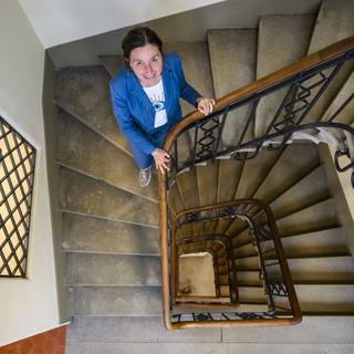 Natacha Litzistorf pose dans un escalier lors d'une conférence de presse sur l'assainissement énergétique des bâtiments de la commune de Lausanne. [Keystone - Jean-Christophe Bott]