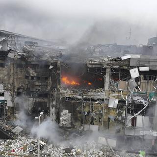 Des pompiers travaillent dans les ruines d'un centre commercial endommagé par l'attaque de missiles la plus massive de la Russie à Dnipro, en Ukraine, le 29 décembre 2023. [Keystone - Service d'urgence ukrainien via AP]