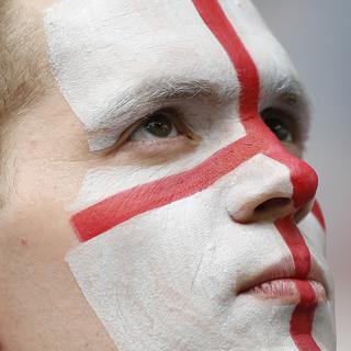 Un fan de football anglais avec le visage peint aux couleurs de la croix de saint George, emblème national de l'Angleterre (image d'illustration). [Keystone/AP Photo - Francisco Seco]