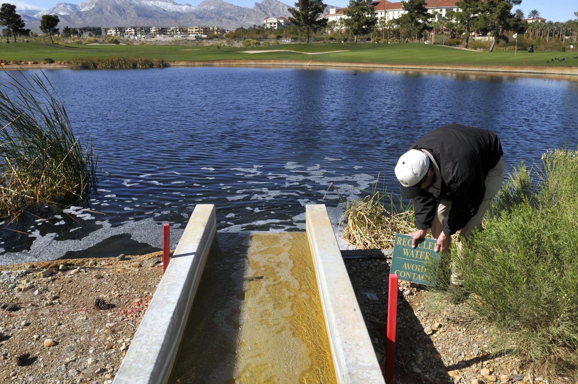 L'intendant d'un golf à Las Vegas remet en place un panneau indiquant que l'étang est constitué d'eau recyclée, le 10 février 2009. [REUTERS - David Becker]
