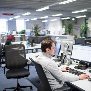 Un homme travaille sur son ordinateur dans un open space. [Keystone - Samuel Trümpy]