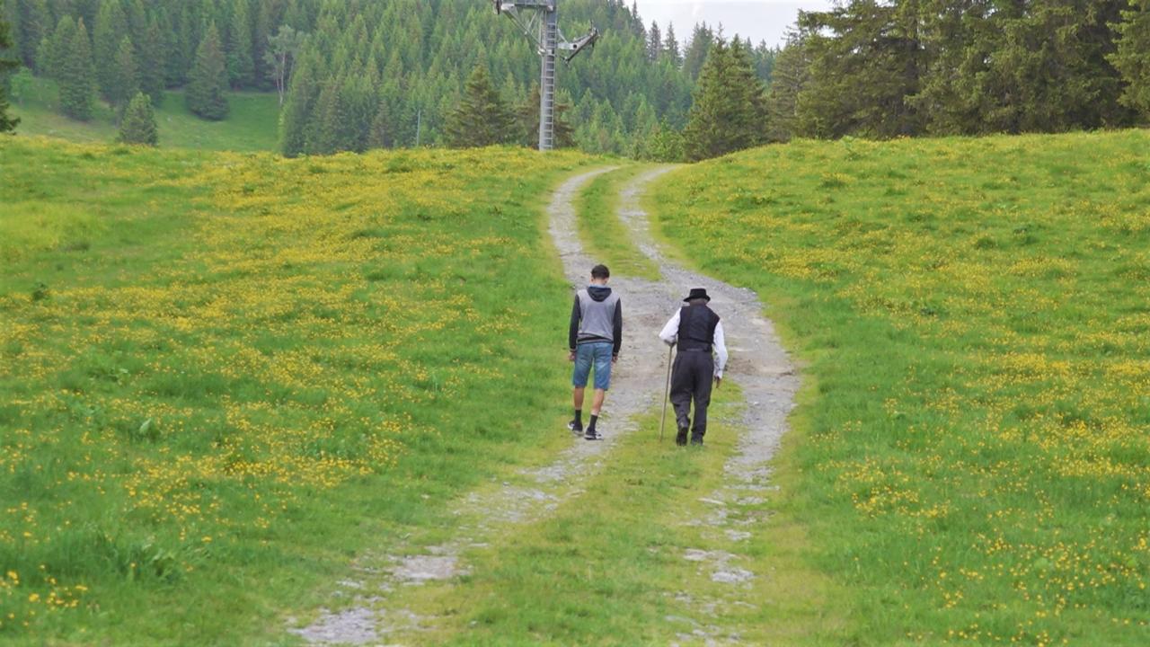 Raphy Guérin montre à son petit-fils un sentier de contrebande qu'il empruntait lorsqu'il était enfant. [RTS]