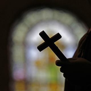 La silhouette d'un crucifix et un vitrail à l'intérieur d'une église catholique de la Nouvelle-Orléans. (image d'illustration) [AP Photo/Keystone - Gerald Herbert]