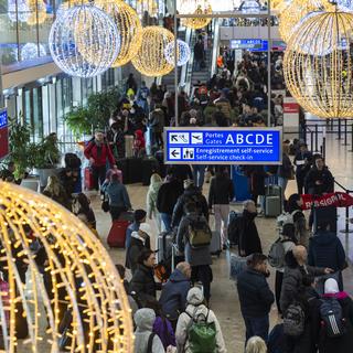 Des passagers à l'aéroport de Genève pendant les fêtes de fin d'année. [Keystone - Martial Trezzini]