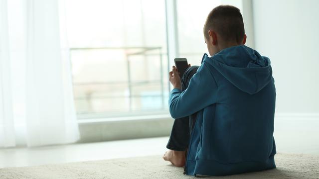 Un enfant bouleversé regarde son smartphone. [Depositphotos - NewAfrica]