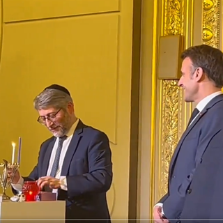 Le grand rabbin de France, Haïm Korsia, en train d'allumer la première bougie du candélabre pour Hanouka en présence d'Emmanuel Macron à l'Elysée. [DR]