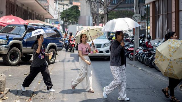 Des habitants de Bangkok se protègent du soleil avec des parapluies en pleine canicule. [AFP - Jack Taylor]