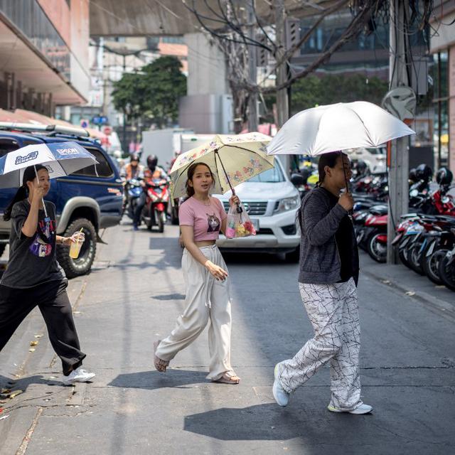 Des habitants de Bangkok se protègent du soleil avec des parapluies en pleine canicule. [AFP - Jack Taylor]