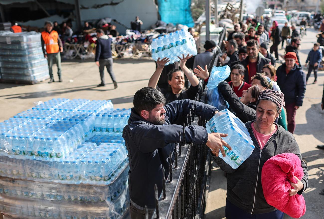 Les gens reçoivent de l'eau un mois après le séisme dévastateur dans le district d'Hatay en Turquie. [Keystone - ERDEM SAHIN]