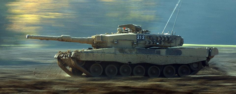 Un char Leopard II suisse roule dans la boue du terrain d'exercice de la place d'armes de Bure, dans le Jura, le jeudi 6 novembre 2003. [Keystone - Gaetan Bally]