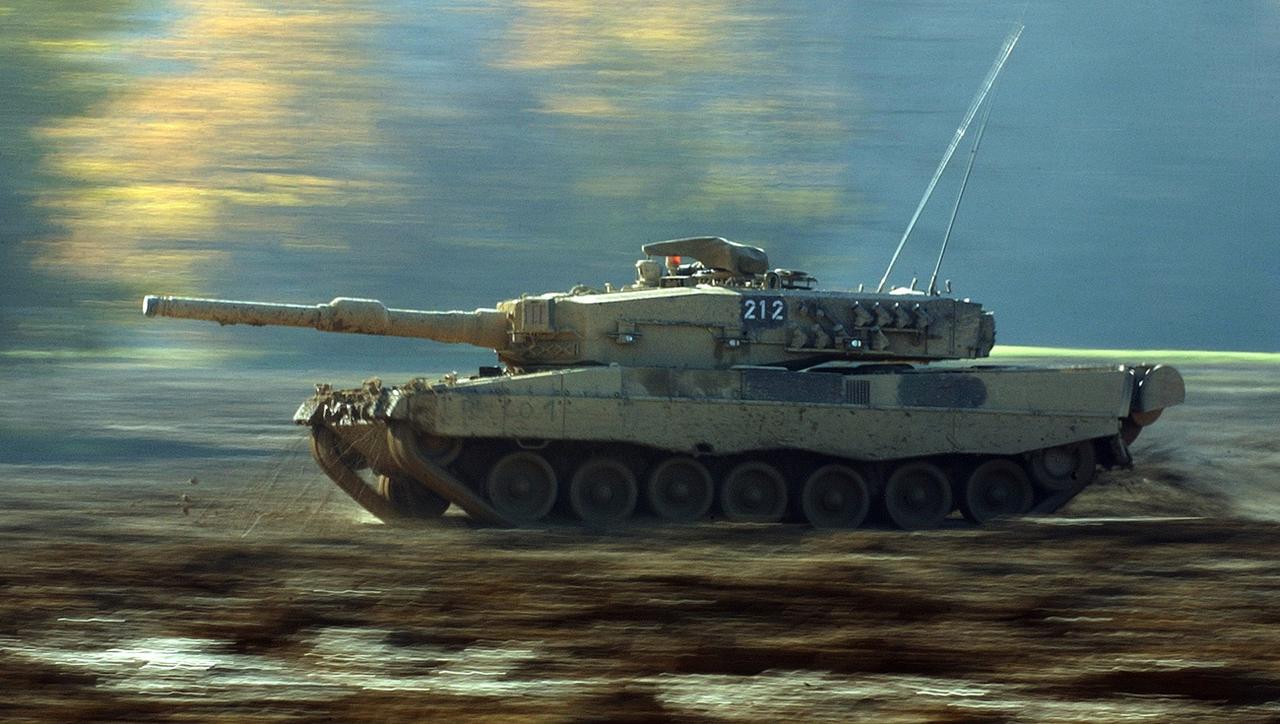 Un char Leopard II suisse roule dans la boue du terrain d'exercice de la place d'armes de Bure, dans le Jura, le jeudi 6 novembre 2003. [Keystone - Gaetan Bally]