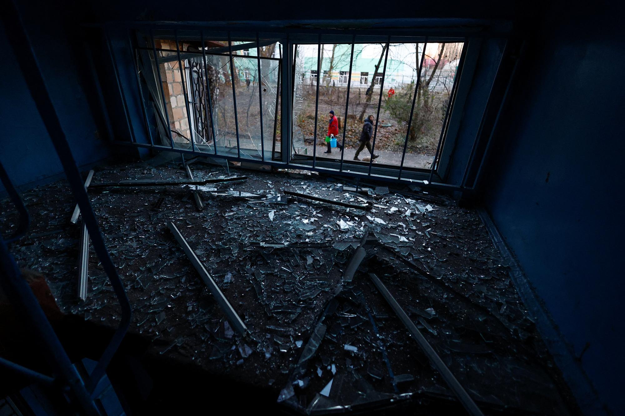 Des résidents locaux marchent devant leur immeuble endommagé par des frappes de drones russes contre Kiev, le 25 novembre 2023. [REUTERS - VALENTYN OGIRENKO]