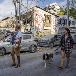 Des personnes israéliennes inspectent les débris causés par un missile du Hamas à Tel Aviv, le 8 octobre 2023. [Keystone/AP Photo - Oded Balilty]