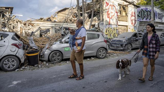 Des personnes israéliennes inspectent les débris causés par un missile du Hamas à Tel Aviv, le 8 octobre 2023. [Keystone/AP Photo - Oded Balilty]