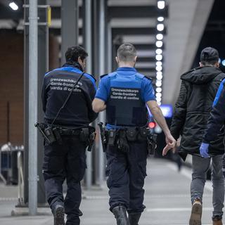 Des gardes-frontières avec un migrant à la gare de Chiasso en février 2023. [Keystone - Ti-Press/Massimo Piccoli]