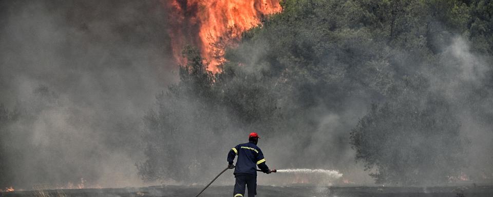 Un pompier luttant contre les gigantesques feux de forêt en Grèce en juillet 2023 (image d'illustration). [Keystone - Vasilis Psomas]