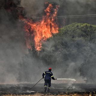 Un pompier luttant contre les gigantesques feux de forêt en Grèce en juillet 2023 (image d'illustration). [Keystone - Vasilis Psomas]