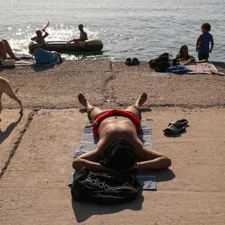 Des gens profitent du soleil à la plage de Kavouri, en Grèce. [EPA/Keystone - GEORGE VITSARAS]