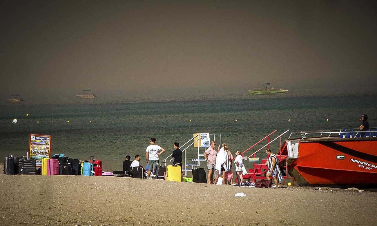 Prévenus par sms, des touristes ont fui sur la plage avec valises et enfants. [Keystone - Argyris Mantikos/Eurokinissi via AP]
