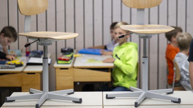 Des chaises encore sur des pupitres, un jour de rentrée scolaire. [Keystone - Peter Schneider]