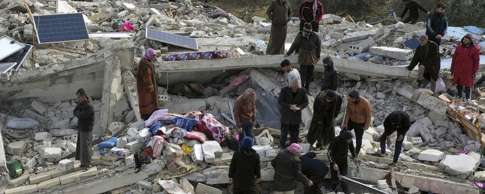 Des civils cherchent des survivants dans les débris des bâtiments d'Idlib, en Syrie. [Keystone - Ghaith Alsayed]