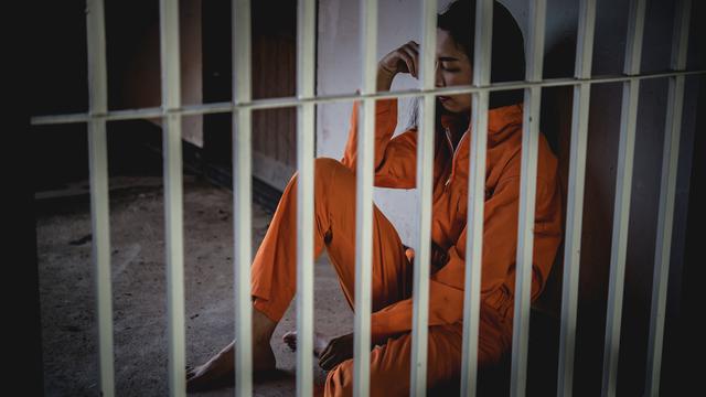 Portrait de femme désespérée d'attraper prison de fer, concept de prisonnier. [Depositphotos - ©Reewungjunerr]
