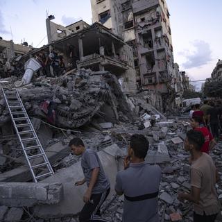 Des Palestiniens recherchent des victimes parmi les bâtiments détruits par des attaques israéliennes à Gaza. [Keystone/AP Photo - Fatima Shbair]