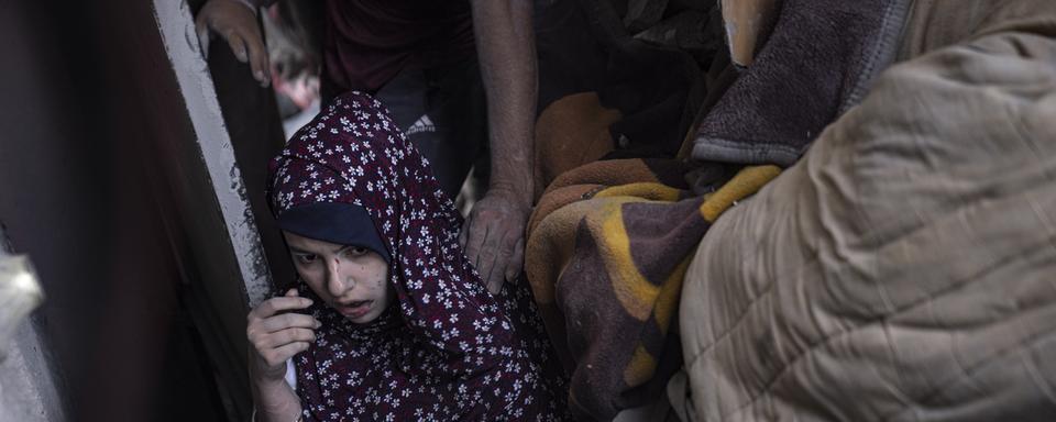 Une femme palestinienne est évacuée d'un immeuble détruit par l'armée israélienne à Gaza, le 5 novembre 2023. [Keystone/EPA - Haitham Imad]