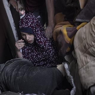 Une femme palestinienne est évacuée d'un immeuble détruit par l'armée israélienne à Gaza, le 5 novembre 2023. [Keystone/EPA - Haitham Imad]