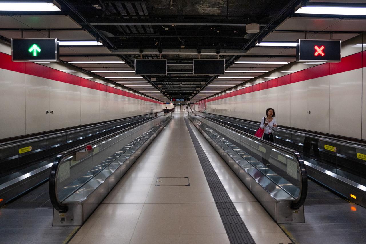 Une femme passe devant la station de MTR Tsim Sha Tsui East vide pendant le typhon Saola à Hong Kong, le 1er septembre 2023. [KEYSTONE - BERTHA WANG]