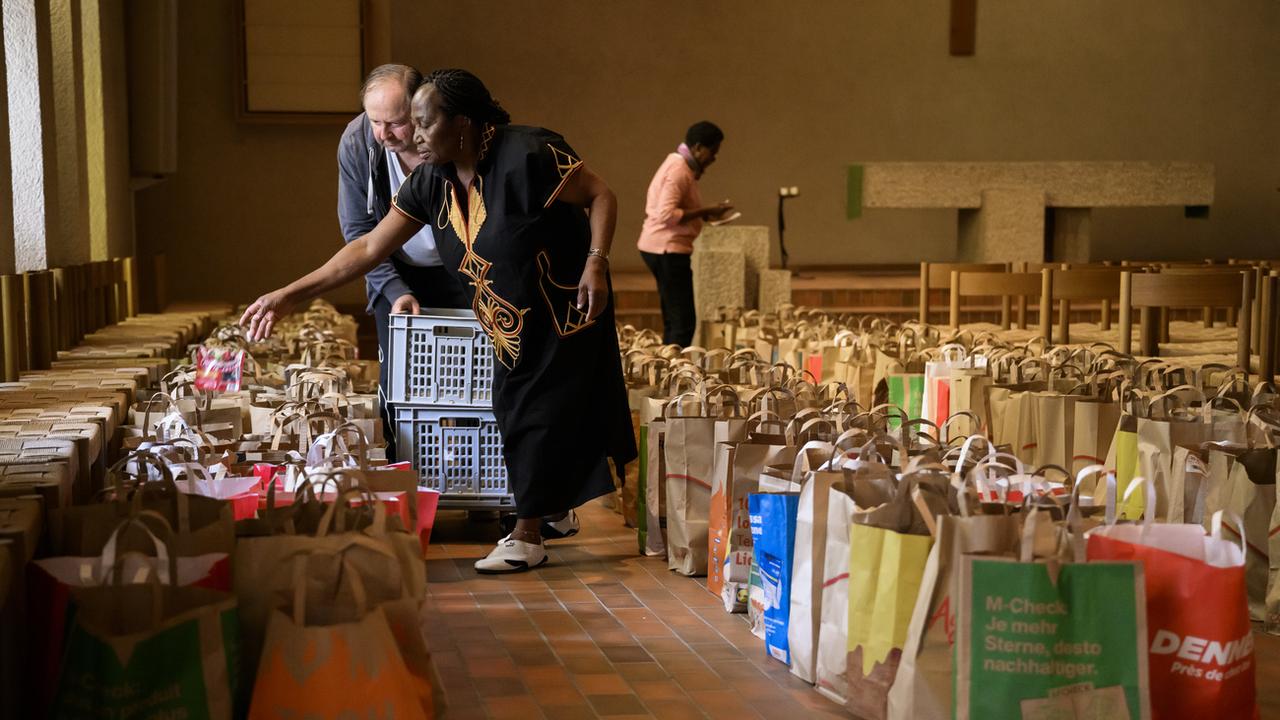 Des bénévoles remplissent des sacs de denrées alimentaires pour une distribution caritative, en octobre 2022 à Lausanne. [Keystone - Jean-Christophe Bott]