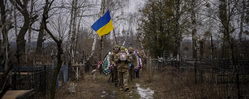 Des militaires ukrainiens transportant le corps d'un lieutenant décédé, vers Kiev. [Keystone/AP Photo - Emilio Morenatti]