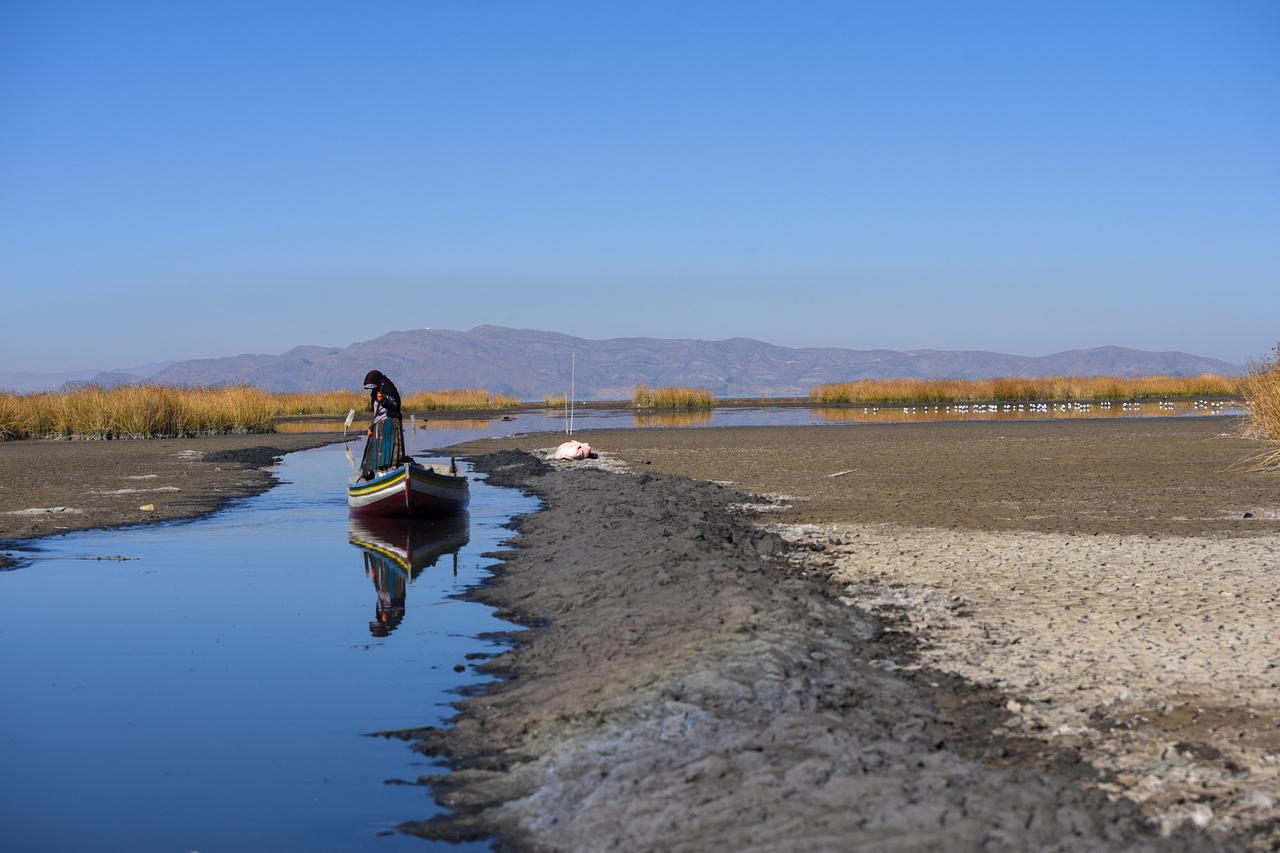 Une pêcheuse fait avancer son bateau dans une voie d'eau étroite près de la rive du lac Titicaca pendant la saison de la sécheresse à Huarina, en Bolivie, le 3 août 2023. [Reuters - Claudia Morales]