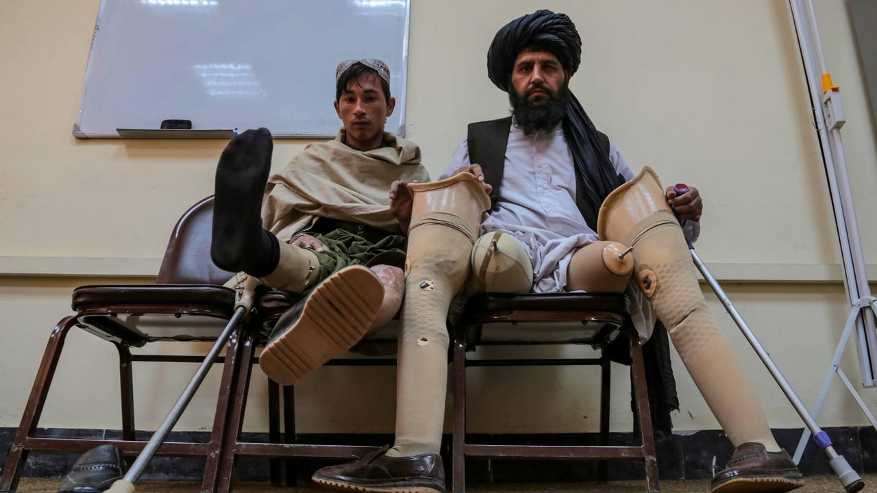 Un homme et son fils, qui ont tous deux perdu leurs membres dans l'explosion d'une mine dans le Helmand, sont assis à Kaboul, en Afghanistan, le 28 décembre 2022. [Keystone - EPA/STRINGER]