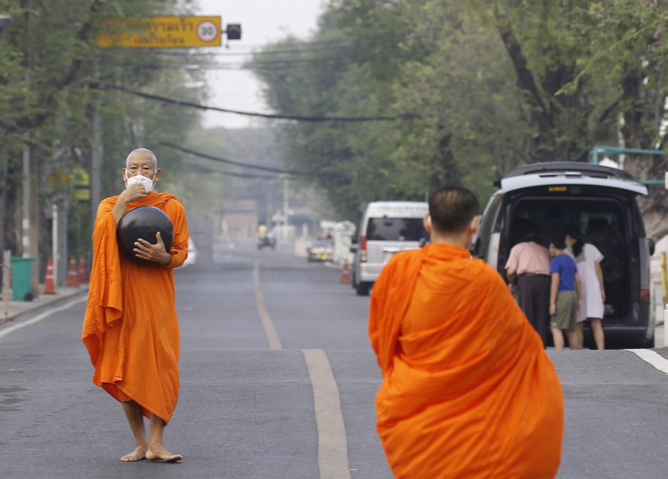 Un moine bouddhiste thaïlandais se couvre le visage avec un masque en raison de la pollution, à l'extérieur d'un temple à Bangkok, le 17 avril 2023. [EPA - Narong Sangnak]