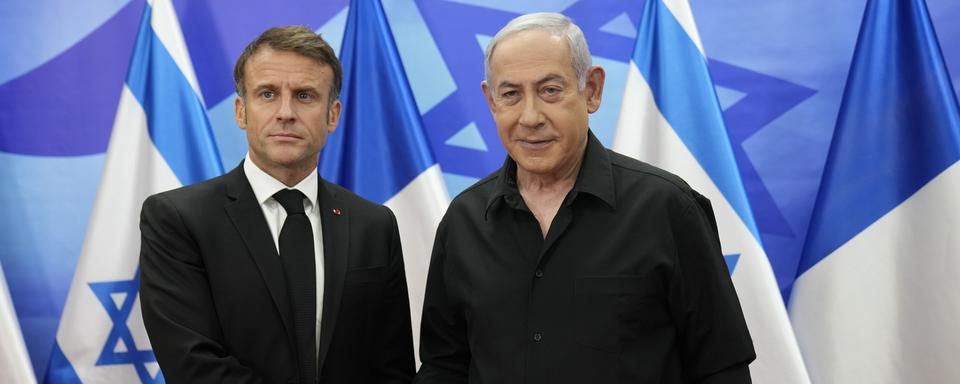 Emmanuel Macron serrant la main de Benjamin Netanyahu lors de sa visite à Jérusalem le 24.10.2023. [EPA/Keystone - Christophe Ena]