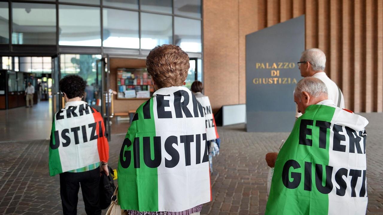 Des proches des victimes de l'amiante d'une usine du groupe Eternit drapés dans des drapeaux italiens sur lesquels sont inscrits les mots Eternit Justice, lors de l'audience du deuxième procès dans l'affaire Eternit à Turin, en Italie, le 24 juillet 2015. [Keystone - Alessandro Di Marco / EPA]