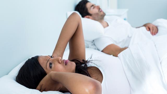 Une femme a du mal à dormir tandis que son compagnon ronfle. [Depositphotos - Wavebreakmedia]