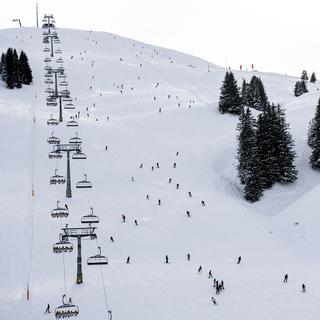 Des skieurs descendent sur une piste du domaine skiable des Portes du Soleil aux Crosets. [Keystone - Jean-Christophe Bott]