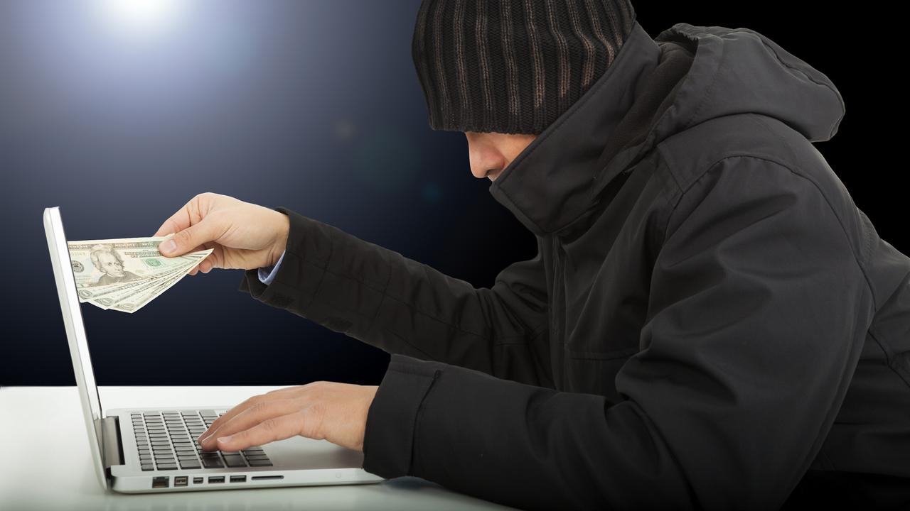 Un arnaqueur en ligne retire de l'argent de son ordinateur. [Depositphotos - Tom Wang]