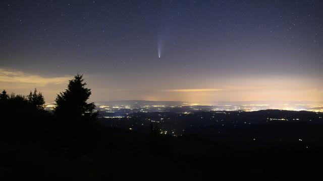 Les Préalpes forment une chambre noire naturelle; une zone de 50 kilomètres carrés est protégée de la pollution lumineuse. La comète Neowise est visible à l'œil nu. Au loin, la pollution lumineuse de la ville de Berne. Col du Gurnigel, le 20 juillet 2020. [Keystone - Anthony Anex]