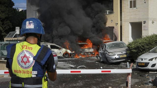 Des voitures brûlent après qu'une roquette tirée depuis la bande de Gaza a touché un parking et un immeuble résidentiel à Ashkelon, dans le sud d'Israël, le samedi 7 octobre 2023. [Keystone - Tsafrir Abayov]