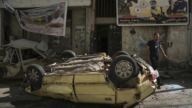 Un homme marche à coté d'une voiture détruite dans le camp de réfugiés de Jénine, en Cisjordanie, le 5 juillet 2023. Image d'illustration. [Keystone - Nasser Nasser/AP Photo]