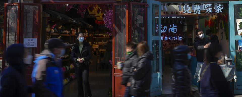 Quelques personnes se baladent devant des boutiques à Beijing en mars 2023. [Keystone/AP Photo - Andy Wong]