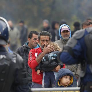 Un homme migrant serre son enfant alors que la police bosnienne les empêchent de traverser la frontière depuis la Croatie. [Keystone/AP Photo - Amel Emric]